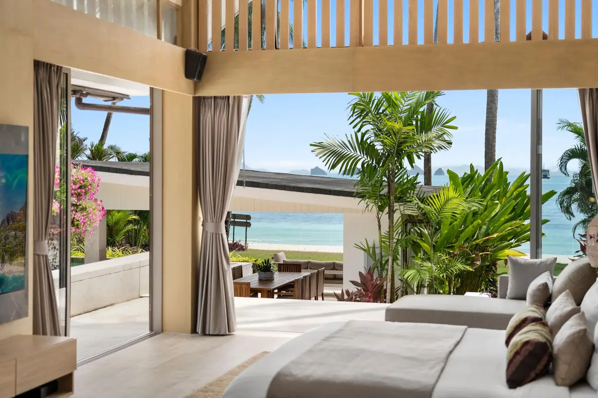 Bedroom 1 at Mandarin Beach Villa: a vaulted garden pavilion with its wide doors open to the pool terrace, palms and Lipa Noi Beach, the bed and a daybed in the foreground.
