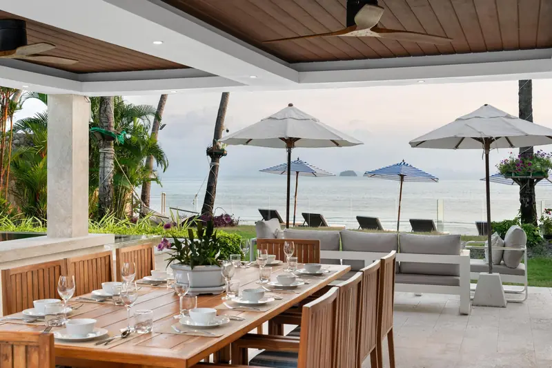 Set outdoor dining table beside the beachfront pool and shaded sea-facing loungers.