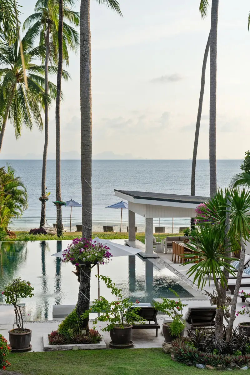 Portrait view past palms and white pavilion roofs to the sea and distant islands.