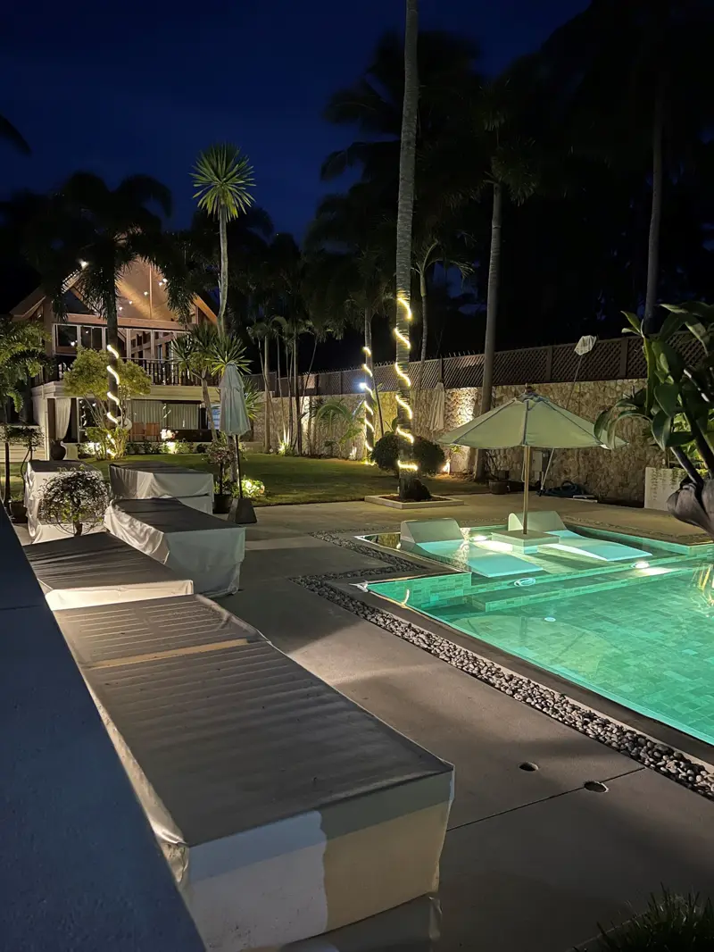 The 18-metre infinity pool lit at night, with the pavilions and palms beyond.