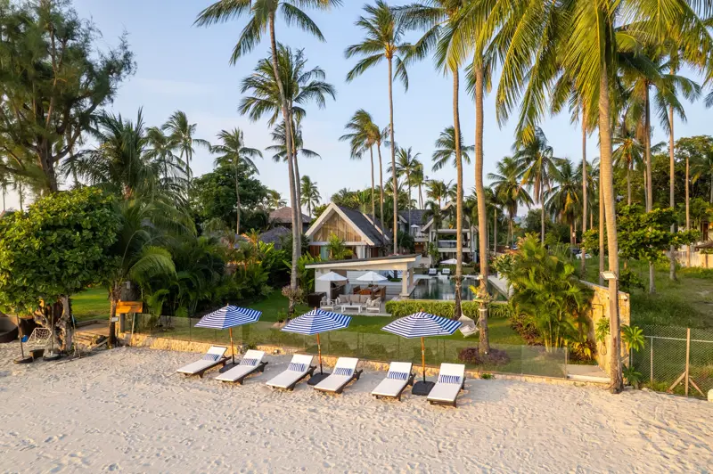 Aerial view of umbrellas and loungers on the sand in front of the lawn.