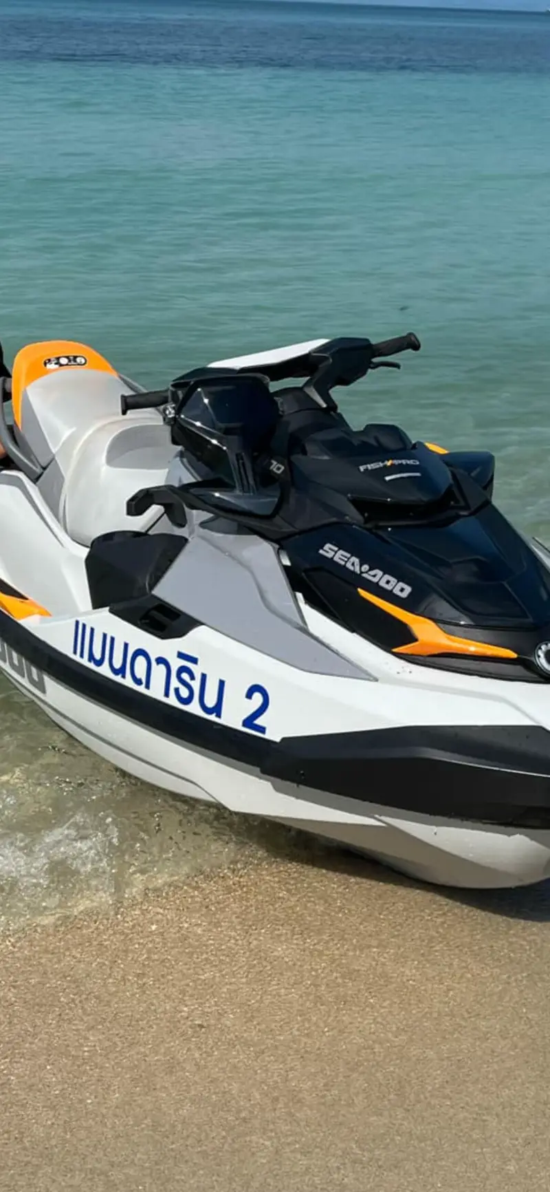 A white and orange Sea-Doo jet ski, named Mandarin 2 in Thai, at the water’s edge.