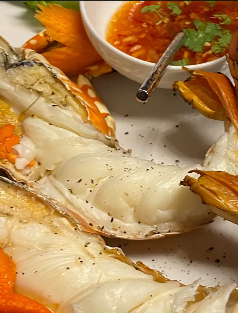 Grilled prawns split and plated with a bowl of chilli dipping sauce, cooked by Mandarin Beach Villa’s chef.
