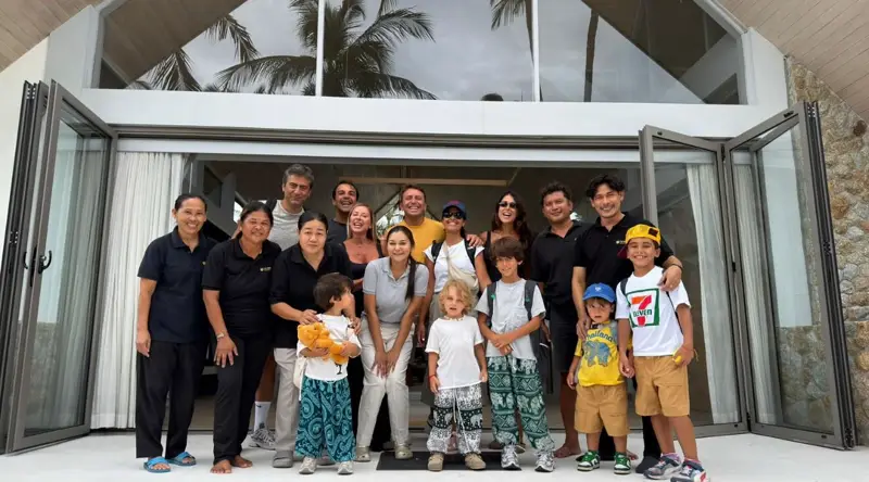 A guest family with children standing with members of the Mandarin Beach Villa team at the glass doors of the main house.