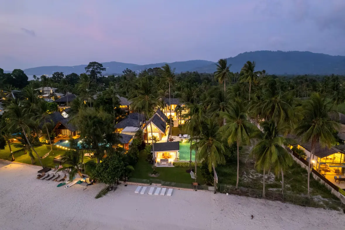 Luxury beachfront family villa illuminated at night with pool and beach views in Koh Samui.